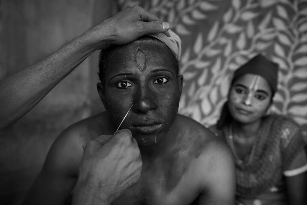 A young boy transforms into the Goddess ‘Kali’ for a festival in a village in Birbhum, West Bengal, India. His face is painted and adorned with patterns. He stares directly out towards the spectator