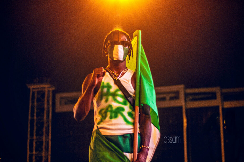 A protester holding a flag with #EndSARS scrawled across his white vest joins thousand in Lagos to protest police brutality.