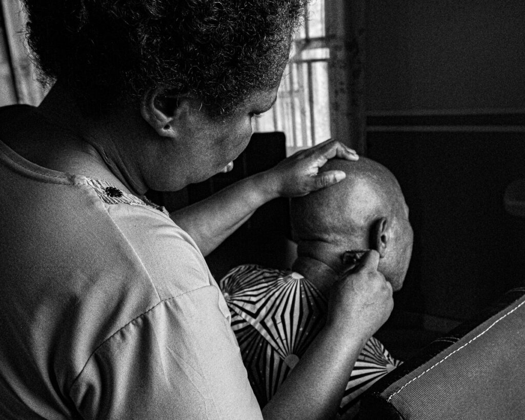 A woman shaves her husband’s head in their home in Ogun, Nigeria.