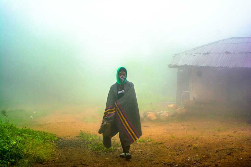 Bolatito emerges through the morning mist at Obake village on the mountain of Erin in Osun state, Nigeria, clad in a heavy shawl and concealed behind a brightly coloured mask