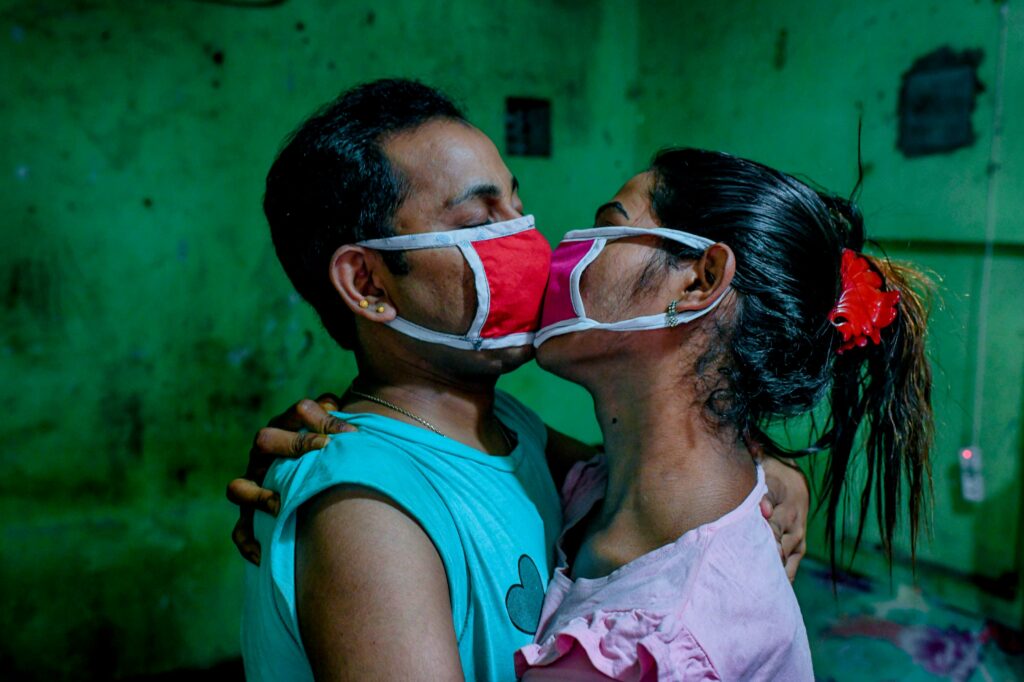 Toma and Tuktuki kiss each other through their masks during the COVID-19 lockdown in Dhaka, Bangladesh.