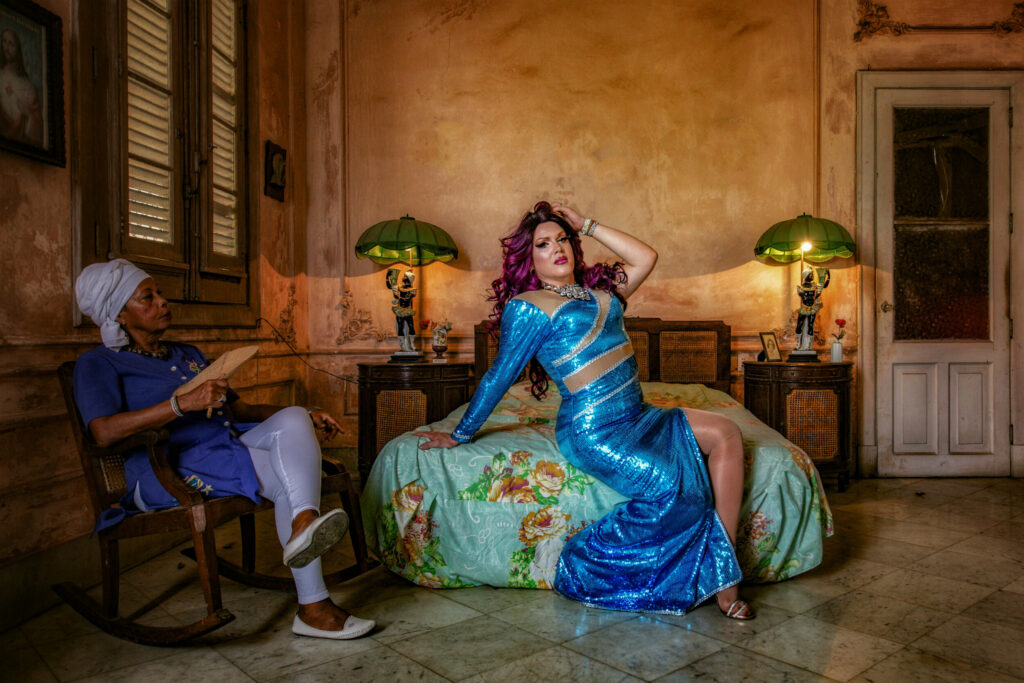 Drag Queen Salma poses on the bed in a room in Cuba.