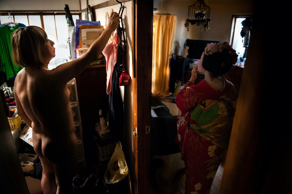 Rosa selects her clothes for a gig later that night. In the next room Usagi, a young geiko apprentice already an expert in drum sound and dolphin dance, touches up her make-up.