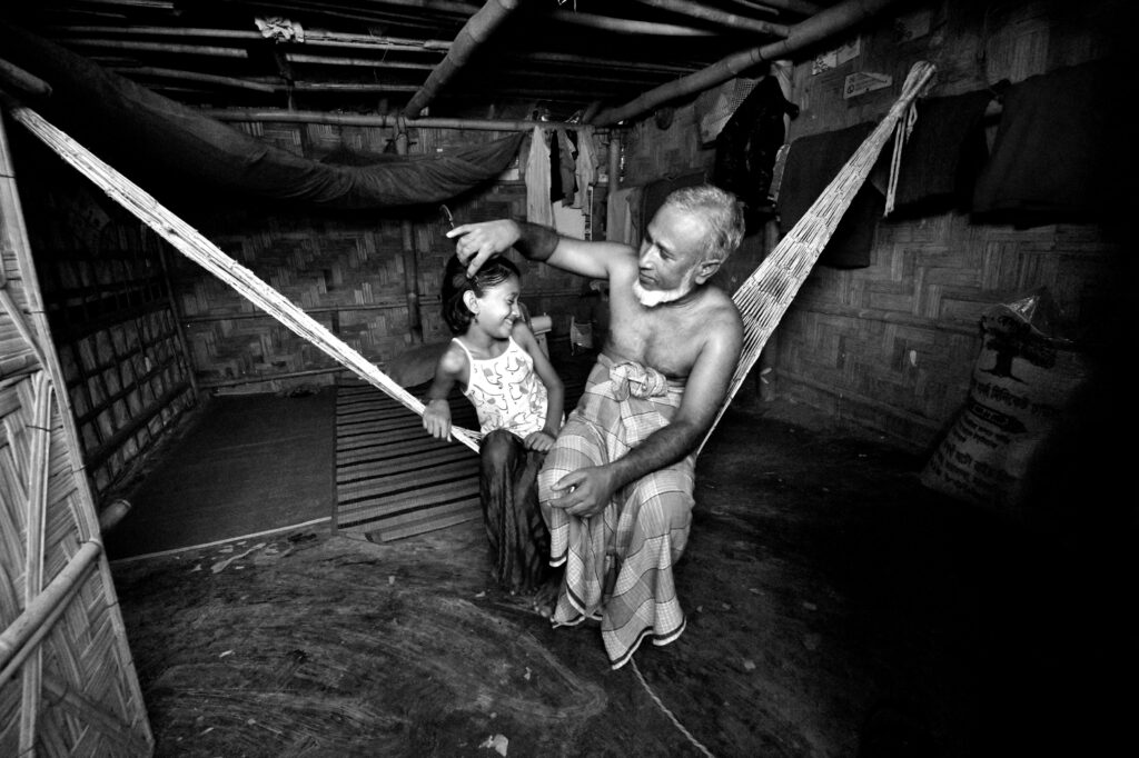 A grandfather gently brushes back his granddaughter’s hair on a makeshift hammock in the Kutupalong Rohingya Refugee Camp, Cox's Bazar, Bangladesh.