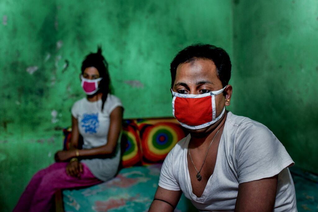 Toma and Tuktuki sit apart on a bed in their shared room. Like many Hijra, the third gender population in Bangladesh, discrimination has forced Toma Tuktuki into sex work.